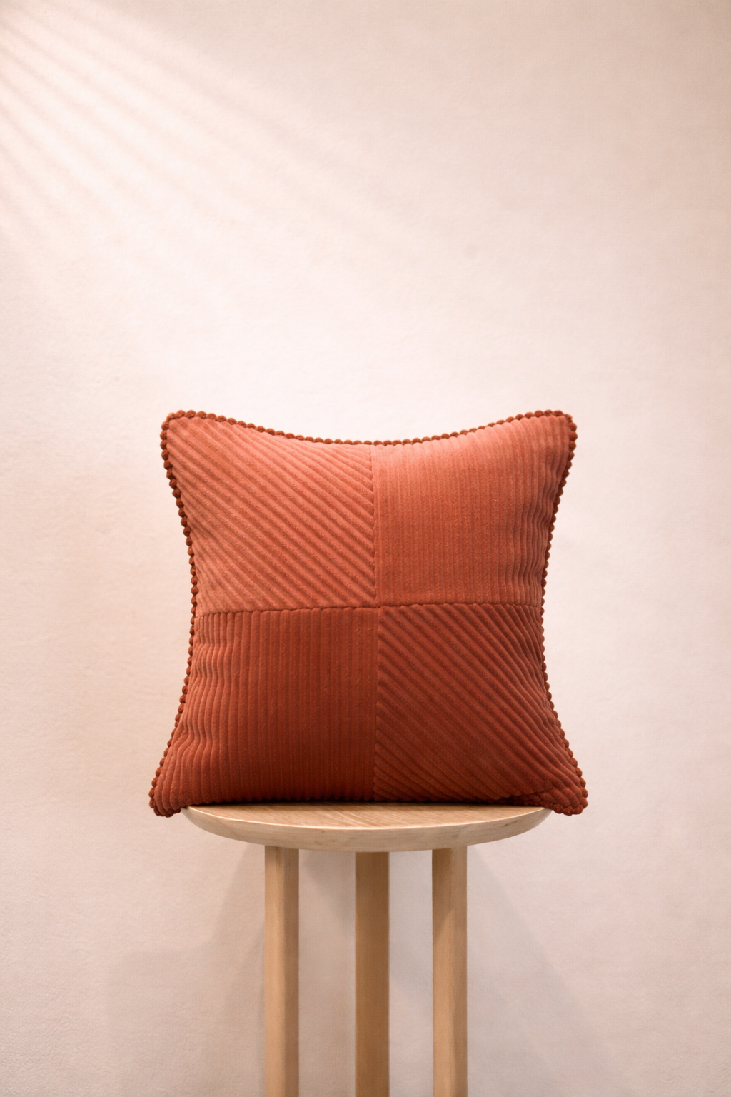 Textured Burnt Terracotta pillow on a wooden stool against a beige background