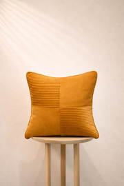 Harvest Gold textured pillow on a white stool against a beige wall