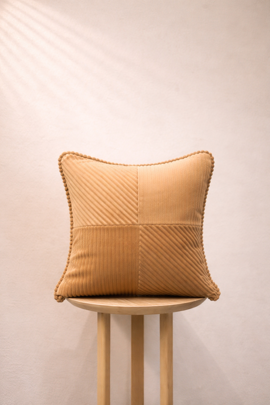 Textured light peach pillow on a wooden stool against a plain background